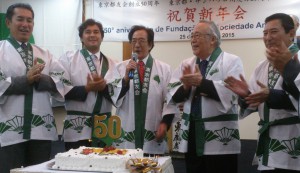 ２０１５年１月２５日にサンパウロ市内のホテルで行われた東京都友会の創立５０周年記念祝賀会で、祝賀ケーキの前に来賓と共にならんだ多羅間名誉会長（右から２人目）