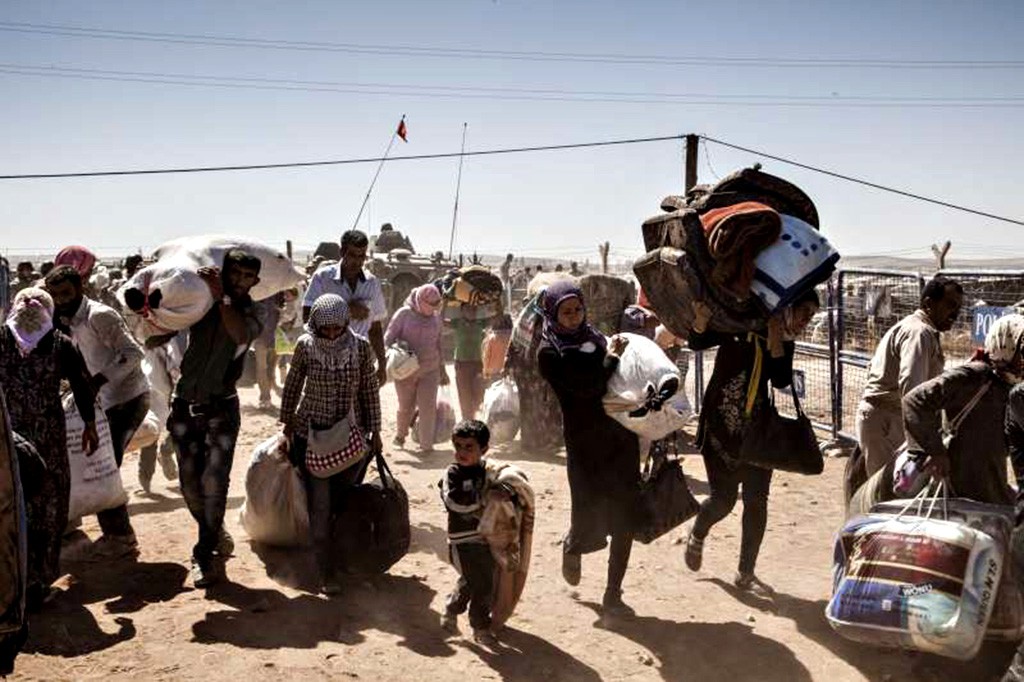 トルコとの国境を歩いて越えるシリアのクルド人難民（I. Prickett/UNHCR）