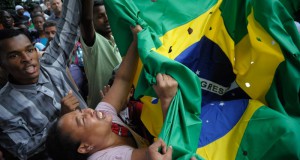 被害者が蜂の巣状態にされた事を穴あきの国旗で表現し、悲しむ参列者達（Fernando Frazao/Agencia Brasil）