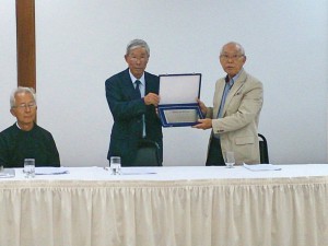 長年の貢献を称え青山新会長（左）から記念プラッカを受け取る山田前会長