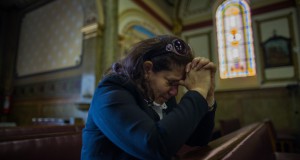 教会で祈るシリアからの女性難民（Victor Moriyama/Vidas Refugiadas/Divulgação）