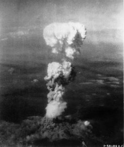 広島に投下された原爆によって巨大なキノコ雲が生じた（米軍機撮影）。キノコ雲の下に見えるのは広島市街、その左奥は広島湾（By Enola Gay Tail Gunner S/Sgt. George R. (Bob) Caron [Public domain or Public domain], via Wikimedia Commons）