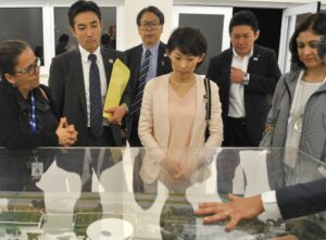 施設の全体模型を前に説明を受ける丸川大臣（中央）