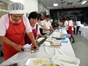 「思いは一つの絆寿司」。巨大な巻き寿司を切り分ける婦人ら