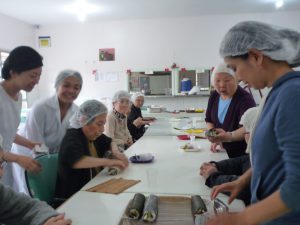 さくらホームで巻き寿司を作る食事イベントの様子（左端が村上さん）