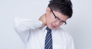 首の痛みを訴えるサラリーマン（写真素材ぱくたそ、www.pakutaso.com、photo すしぱく）