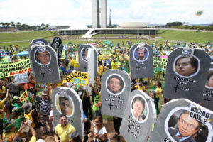 政治家や企業家の顔写真を掲げて、汚職反対デモを行う人々（Antonio Cruz/Agência Brasil）