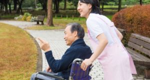 屋外の車椅子の男性と介護士（日本、フリー写真サイト「写真AC」より）