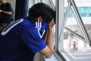 試合終了後、泣き顔を隠して窓際にたたずむ男性