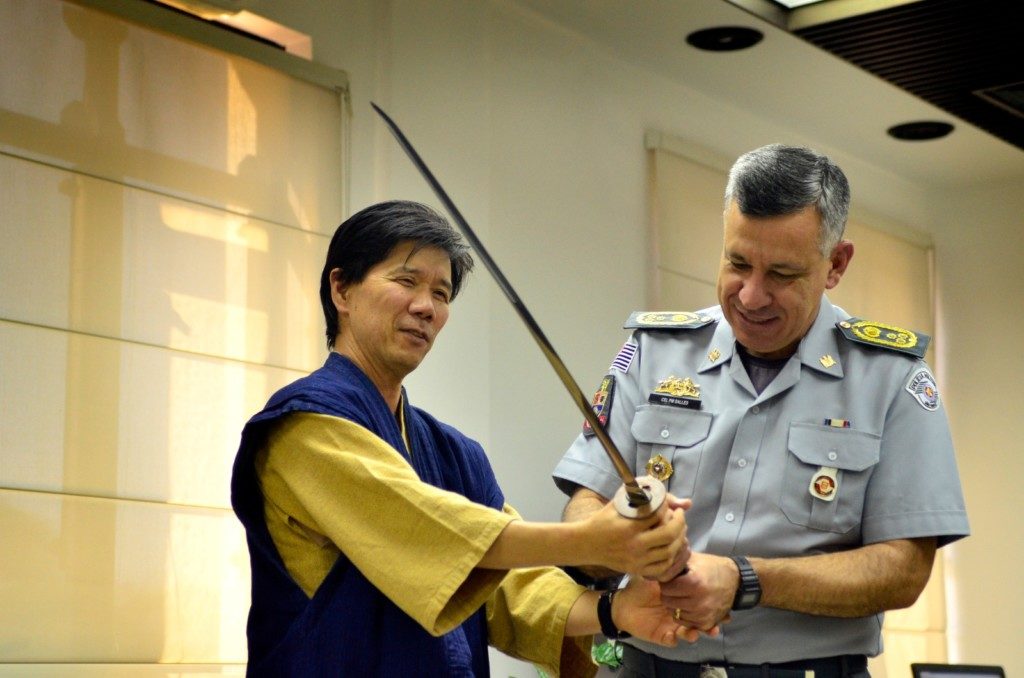 マルセロ・ヴィエイラ・サーレス大佐に日本刀を見せる岸川さん（提供写真）