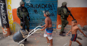 ライフルを持った兵士の横を半裸の子供が平気で歩いている。（Fernando Frazao / Agencia Brasil）