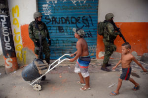 ライフルを持った兵士の横を半裸の子供が平気で歩いている。（Fernando Frazao / Agencia Brasil）