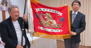 大山康晴氏寄贈の優勝旗を授与する山田大使（右）と高嶋さん（左）