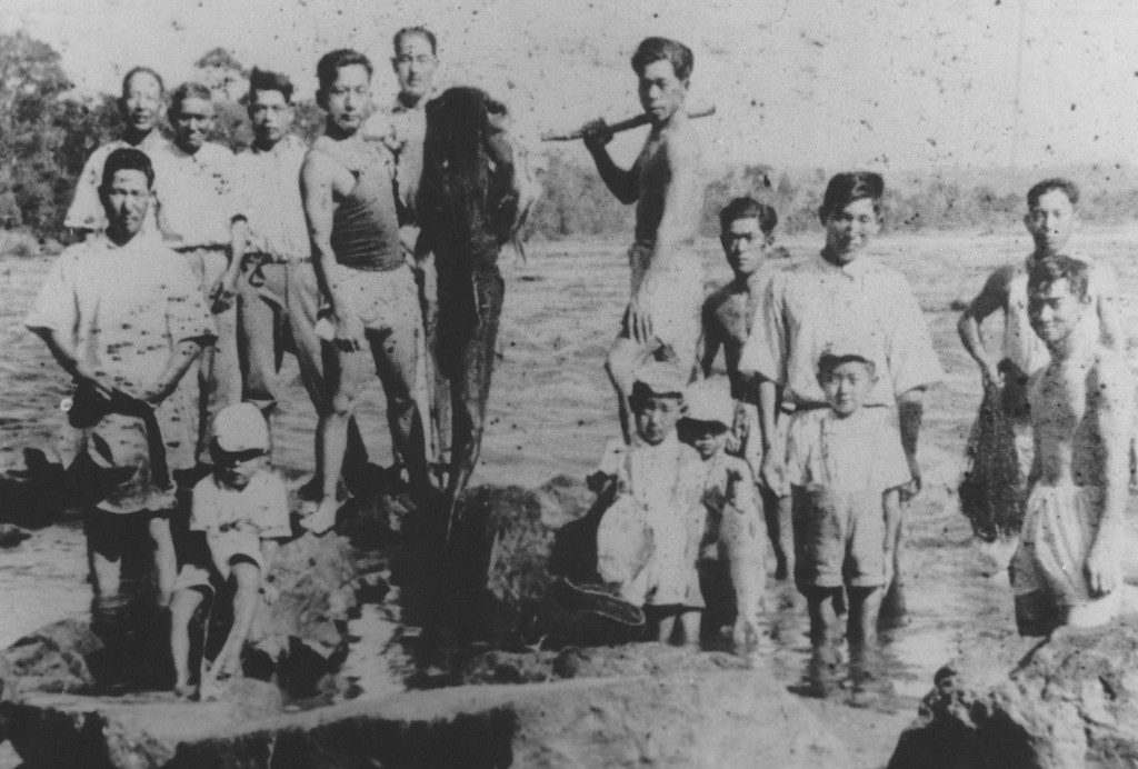 戦後、日本に帰国する人の送別会の様子。釣り上げた巨大魚で門出を祝った。魚の後ろに立つ面長の男性とその家族が帰国した