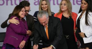 マルセラ夫人や女性議員らに囲まれ、家庭内暴力廃絶計画にサインする大統領（Marcos Corrêa/PR）