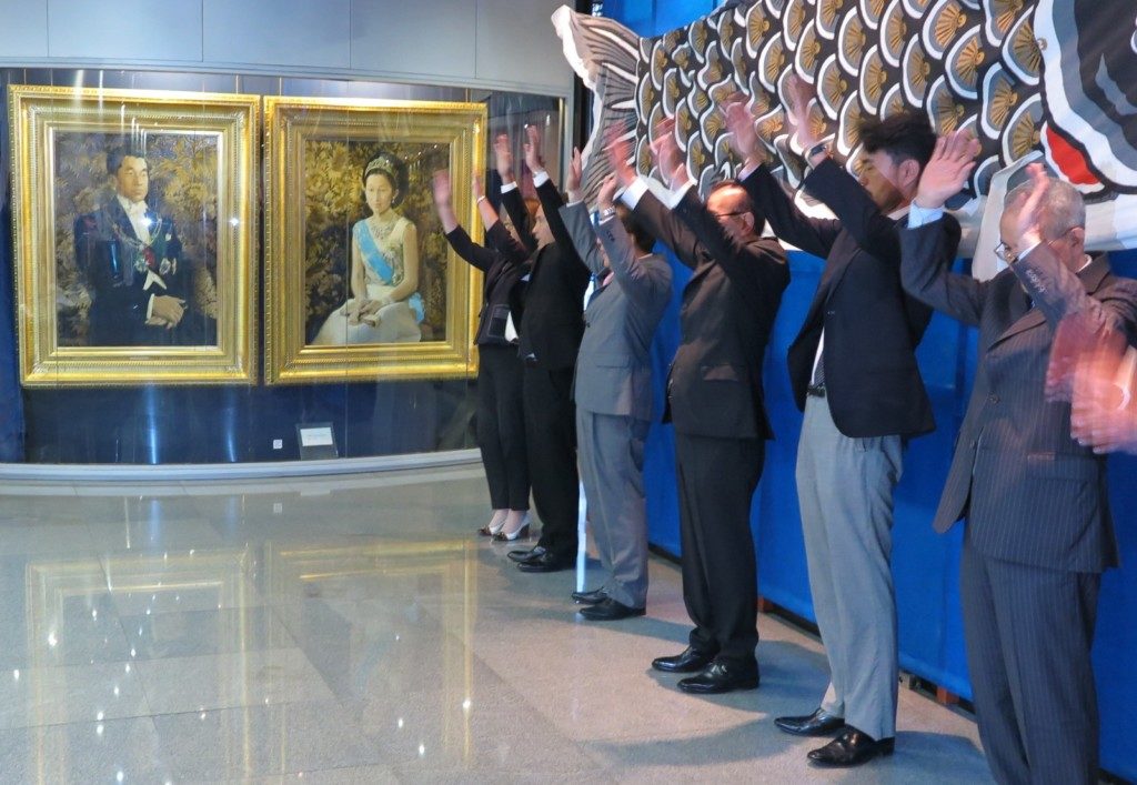 お二人の肖像画の前でバンザイ三唱する日系団体代表者ら