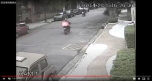 事件近くの防犯カメラの映像で被害者を襲う直前の強盗二人。一方通行の路を逆走するバイクと右上あたりで路肩に停止しているバイク（在サンパウロ総領事館からの注意喚起メール添付動画より）