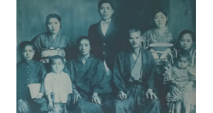 １９３７年―安慶名家の家族写真。次男信綱を膝にのせているのが篤成の妻カマド。左側で、白いシャツを着ている子が長男篤政。前列中央が篤成の父金次郎、その左母マツ、左端篤成の弟恒信(三男)。後列中央が篤成の兄篤信(長男)、その左が篤成の妹サダ、右がカマドの友人